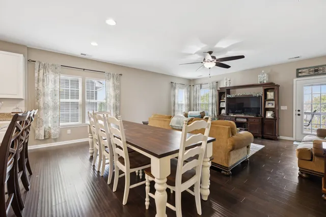 a kitchen with stainless steel appliances kitchen island granite countertop a stove a sink a refrigerator and a dining table with wooden floor