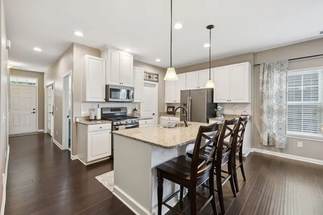 a kitchen with stainless steel appliances granite countertop a stove top oven a sink island and a refrigerator