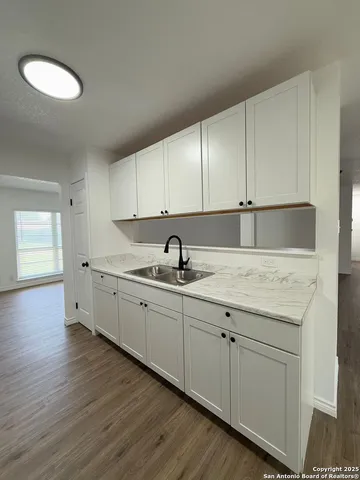 a kitchen with granite countertop white cabinets and a sink