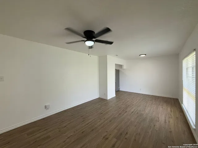 an empty room with wooden floor and a ceiling fan