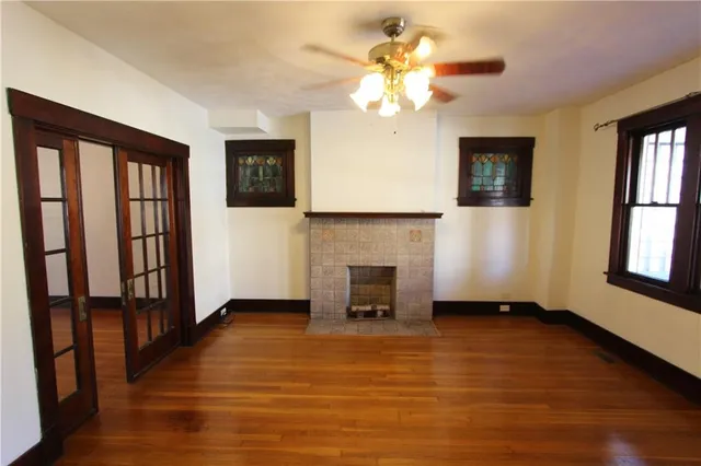 a view of an empty room with wooden floor and a fireplace