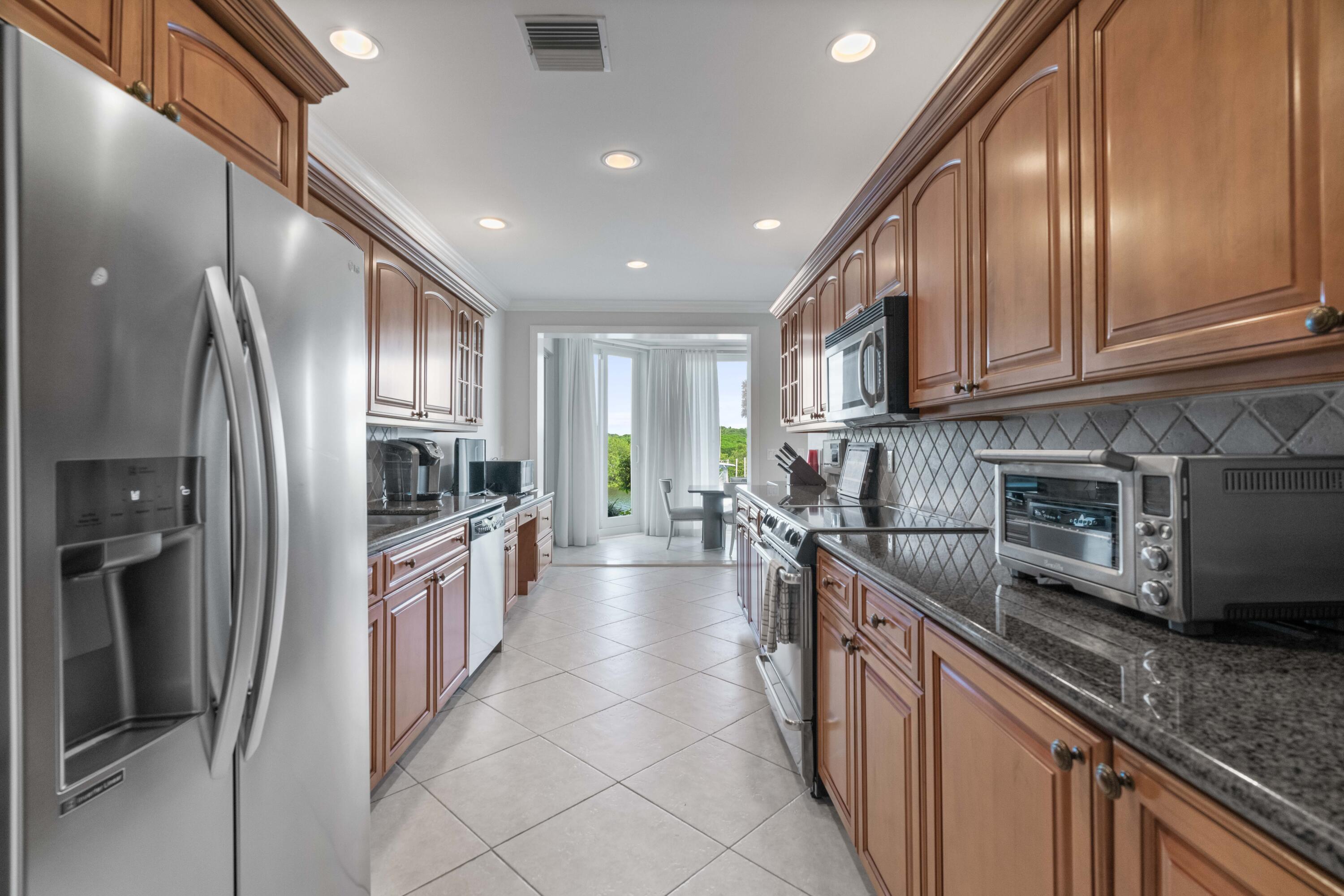 266 Eagle Drive Jupiter, FL 33477 - Photo 8 of 35 a kitchen with stainless steel appliances granite countertop a refrigerator a stove a sink and a microwave
