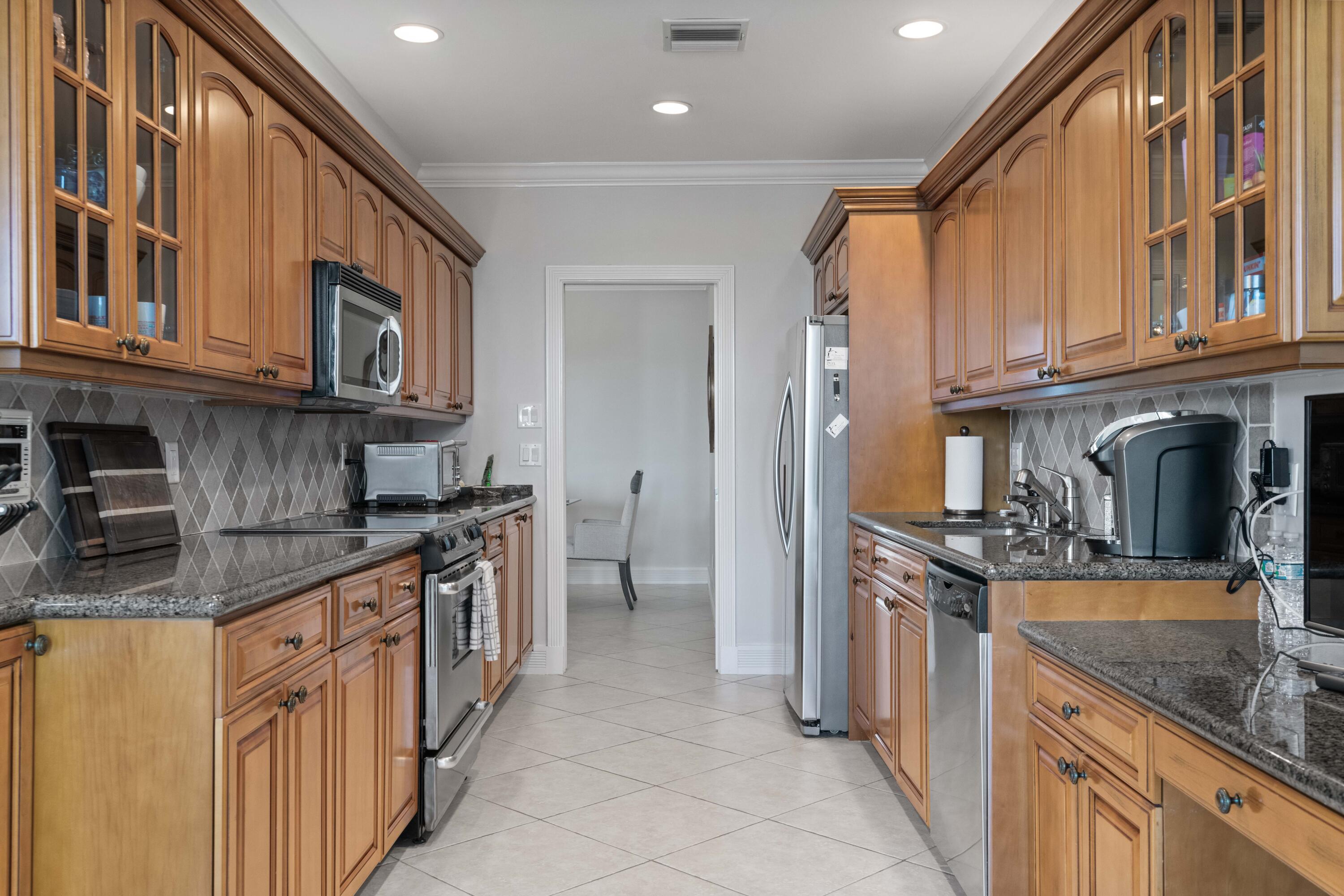 266 Eagle Drive Jupiter, FL 33477 - Photo 9 of 35 a kitchen with stainless steel appliances granite countertop a sink and dishwasher a stove top oven with wooden floor