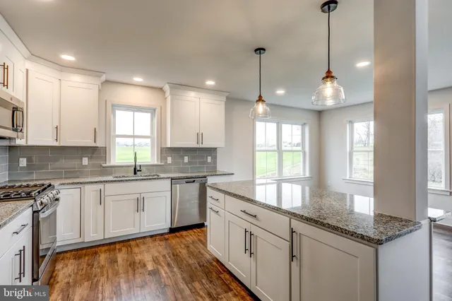 a kitchen with granite countertop white cabinets white appliances a sink and a window