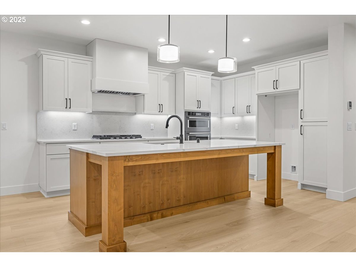 3518 North 11th Circle Ridgefield, WA 98642 - Photo 10 of 44 a kitchen with kitchen island granite countertop a stove a sink a refrigerator and white cabinets with wooden floor
