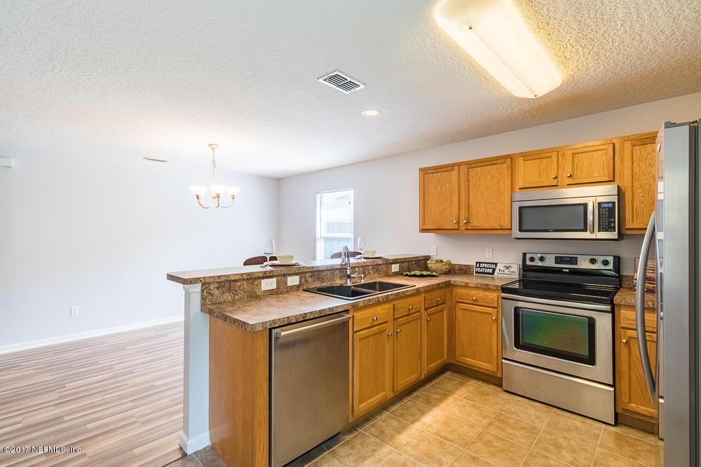 13290 Pacemaker Drive Jacksonville, FL 32225 - Photo 7 of 40 a kitchen with stainless steel appliances granite countertop wooden cabinets stove top oven and sink