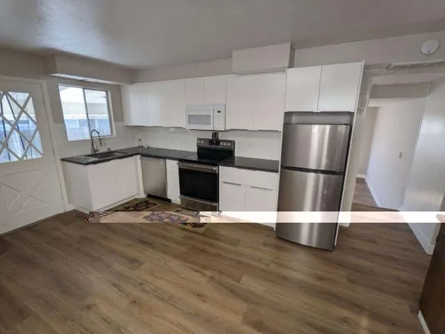 a kitchen with granite countertop a refrigerator and a stove top oven