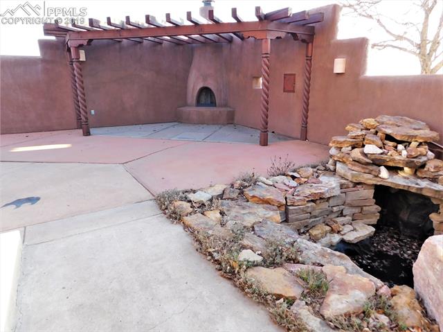 4320 Meridian Road Peyton, CO 80831 - Photo 28 of 28 At the front door you will find an entertaining patio w Kiva fireplace and pond w waterfall