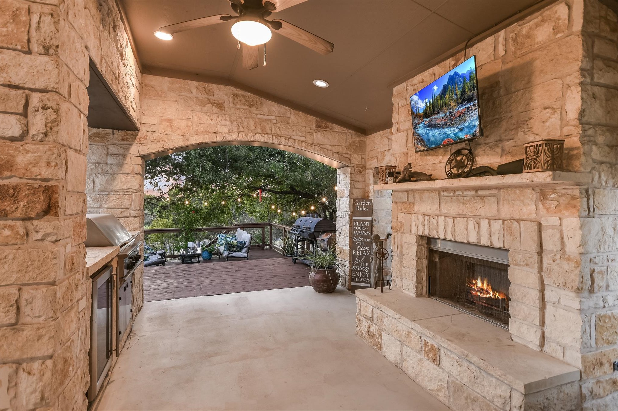 300 Wesley Ridge Drive Spicewood, TX 78669 - Photo 5 of 40 This outdoor retreat combines comfort and style with a stone fireplace, mounted TV, and built-in grill.