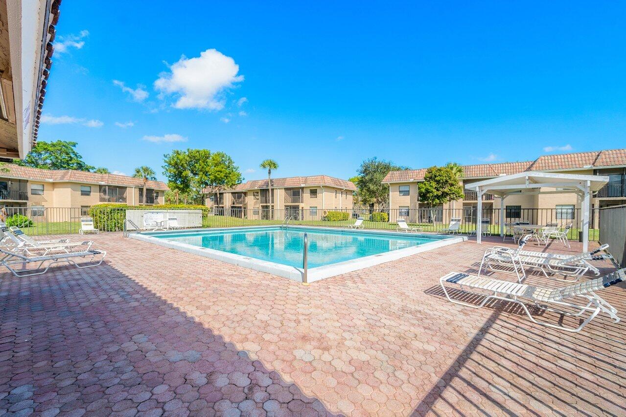6736 Palmetto Circle South, Unit 105 Boca Raton, FL 33433 - Photo 25 of 28 a swimming pool with outdoor seating and yard