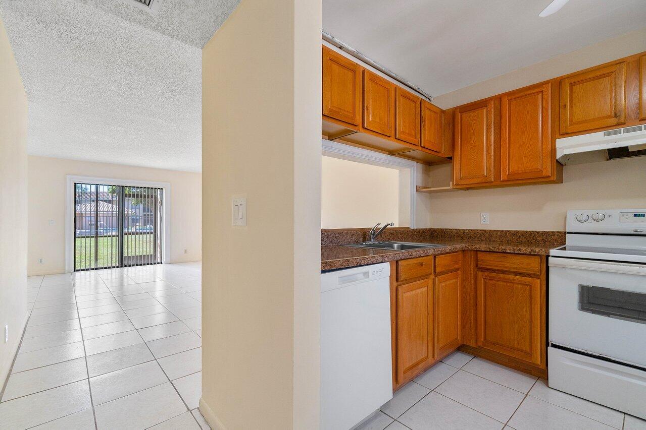 6736 Palmetto Circle South, Unit 105 Boca Raton, FL 33433 - Photo 7 of 28 a kitchen with stainless steel appliances granite countertop a refrigerator and a stove top oven