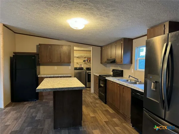 a kitchen with stainless steel appliances kitchen island granite countertop a refrigerator a sink a stove and blue cabinets