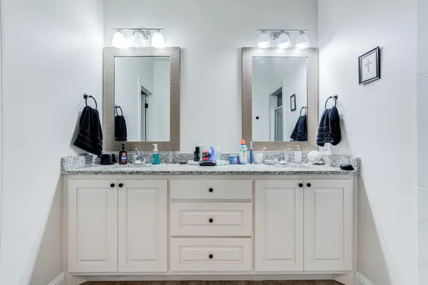 a bathroom with double vanity white cabinets and a mirror
