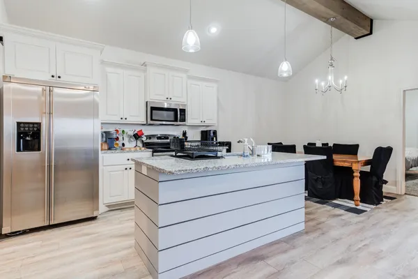 a kitchen with stainless steel appliances kitchen island granite countertop a refrigerator a stove a sink dishwasher and a refrigerator with wooden floor