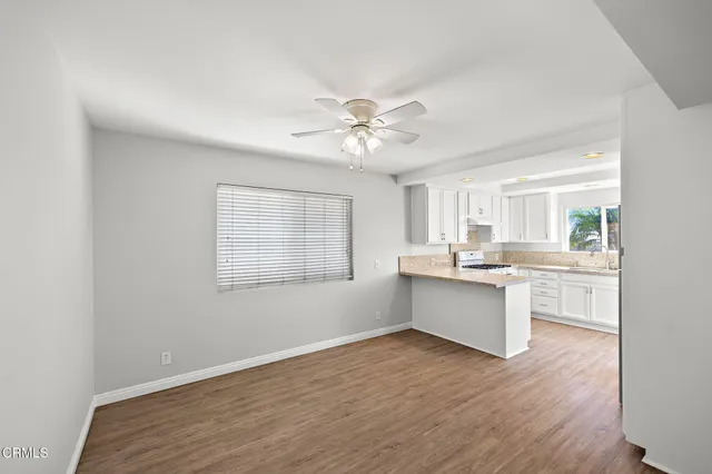 a large white kitchen with sink wooden floor and a kitchen island