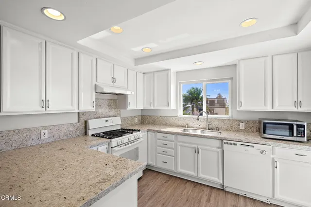 a kitchen with granite countertop a sink a stove and cabinets