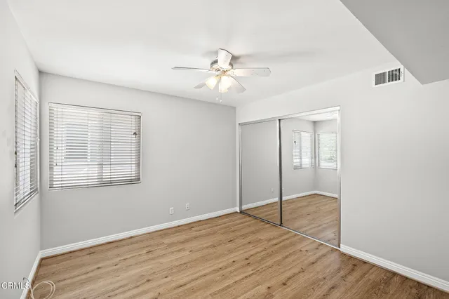 a view of empty room with wooden floor and fan