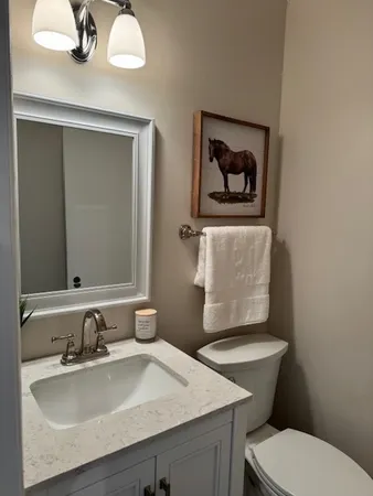 a bathroom with a granite countertop toilet a sink and mirror