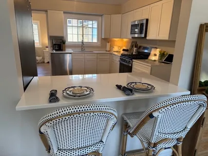 a kitchen with granite countertop wooden floors stainless steel appliances and white cabinets