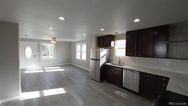 a kitchen with stainless steel appliances granite countertop a sink a stove a refrigerator cabinets and wooden floor