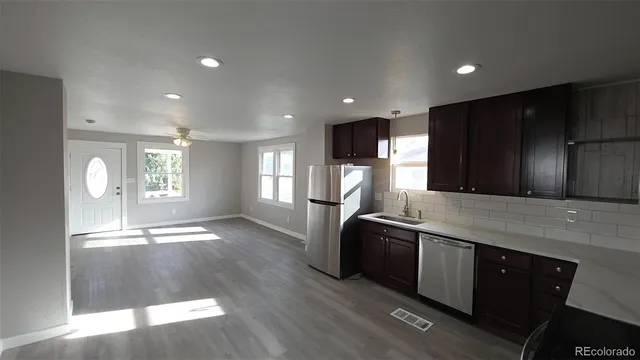 a kitchen with stainless steel appliances granite countertop a sink a stove a refrigerator cabinets and wooden floor