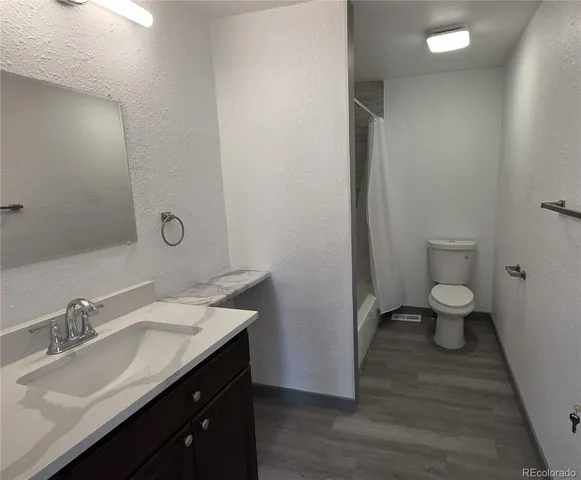 a spacious bathroom with a granite countertop sink a toilet and a mirror