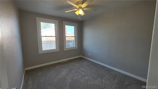 an empty room with a window and a fan