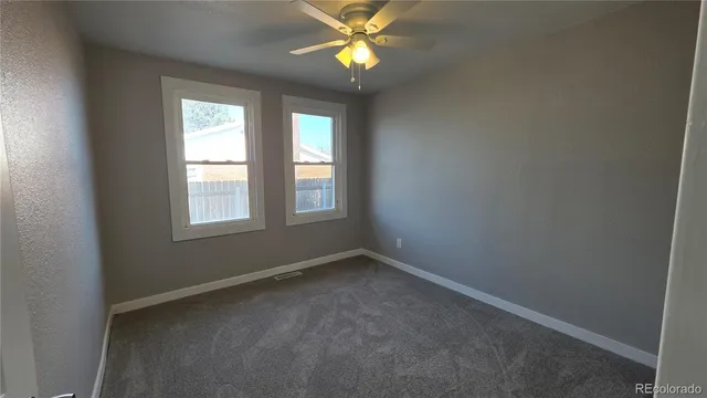 an empty room with a window and a fan