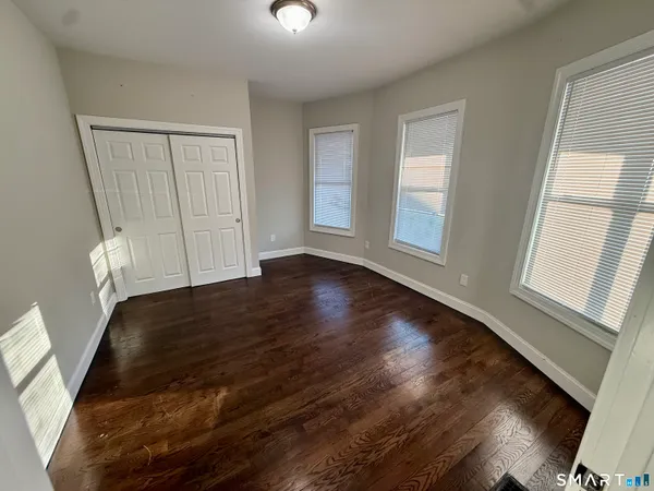 a view of an empty room with wooden floor and a window
