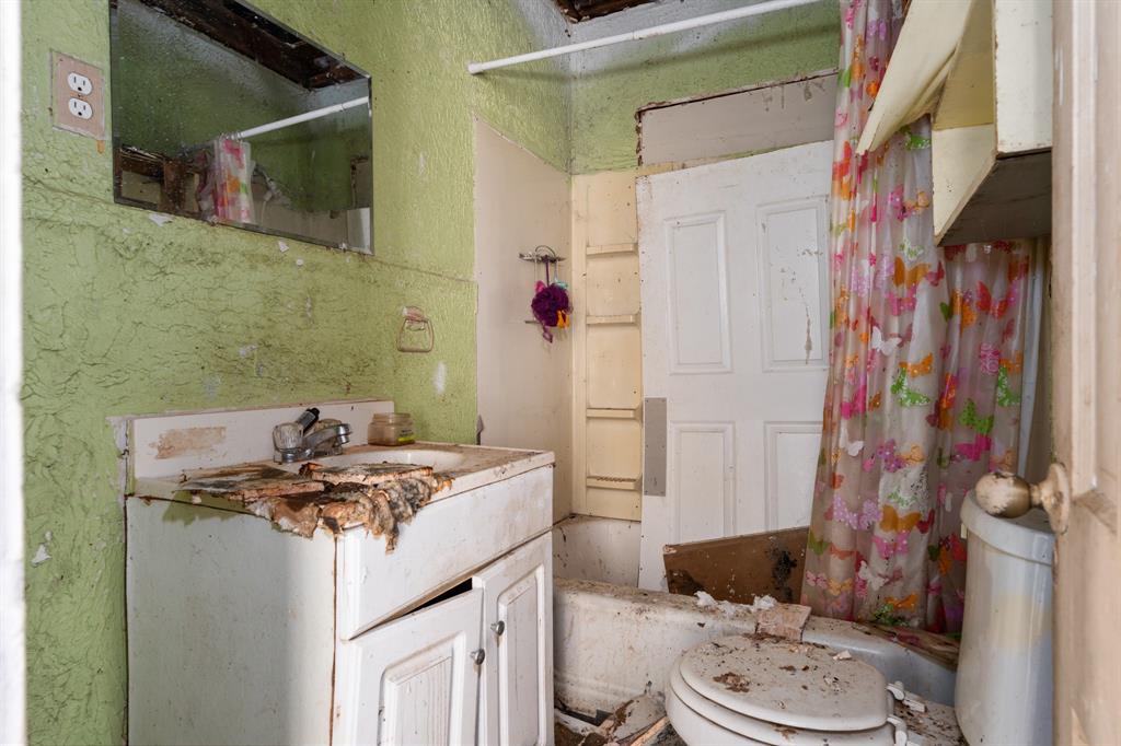 218 North Preston Street Whitney, TX 76692 - Photo 19 of 23 a bathroom with a granite countertop sink a toilet and shower curtain