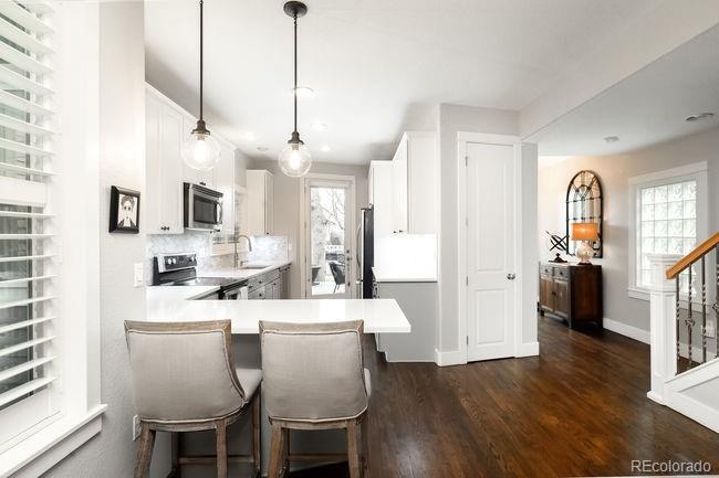 3604 Raleigh Street Denver, CO 80212 - Photo 11 of 38 a kitchen with stainless steel appliances kitchen island granite countertop a refrigerator a stove a sink dishwasher and white cabinets with wooden floor