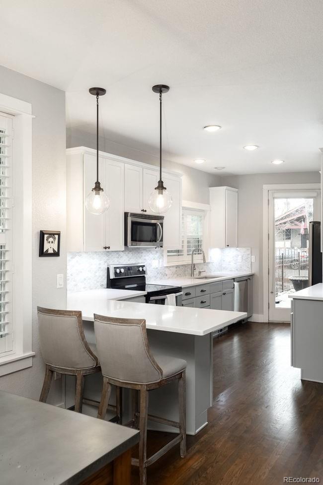 3604 Raleigh Street Denver, CO 80212 - Photo 12 of 38 a kitchen with stainless steel appliances kitchen island a stove a sink dishwasher a microwave oven and a dining table with wooden floor
