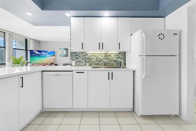 a kitchen with white cabinets and refrigerator