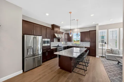 a kitchen with stainless steel appliances granite countertop a refrigerator a sink a stove a microwave and wooden floor