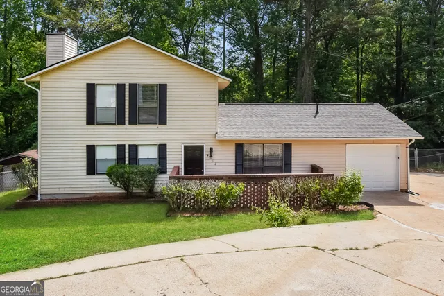 a view of a house with a yard plants and large tree