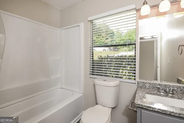 a bathroom with a granite countertop toilet a sink and a bathtub