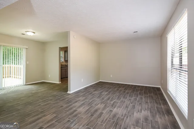an empty room with wooden floor and windows