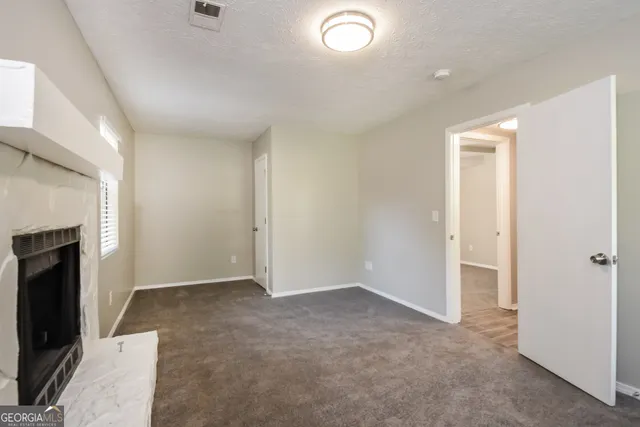 an empty room with windows and fireplace