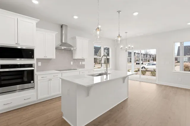 a large kitchen with kitchen island a stove a sink a center island and wooden floor