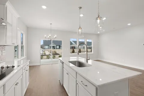 a large white kitchen with a large window a sink and stainless steel appliances