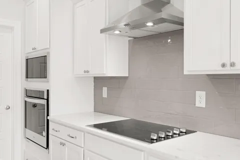 a kitchen with granite countertop white cabinets and stainless steel appliances
