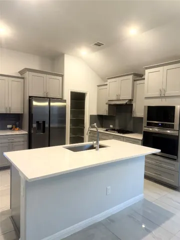 a large kitchen with stainless steel appliances a refrigerator a stove and microwave