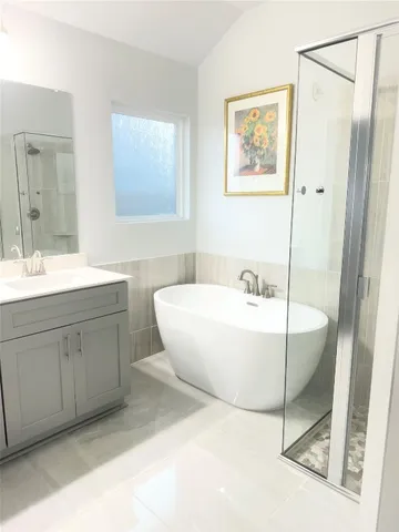 a spacious bathroom with a tub sink shower and mirror