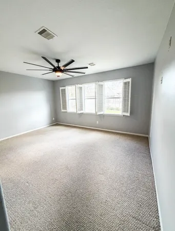 an empty room with windows and fan
