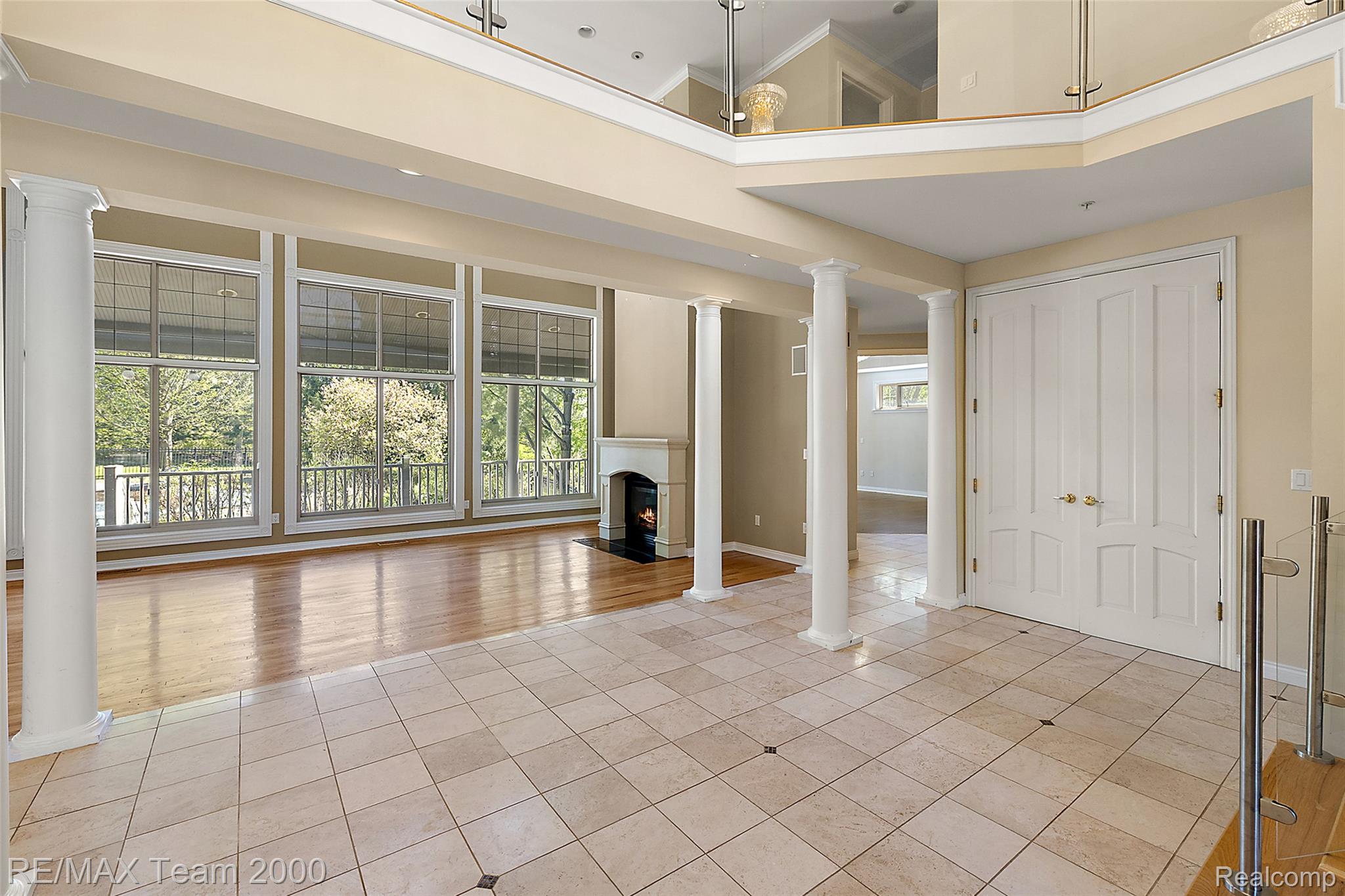 630 Sheldon Court Rochester, MI 48306 - Photo 14 of 94 Unfurnished living room with decorative columns, light tile patterned floors, a high ceiling, and a fireplace with flush hearth