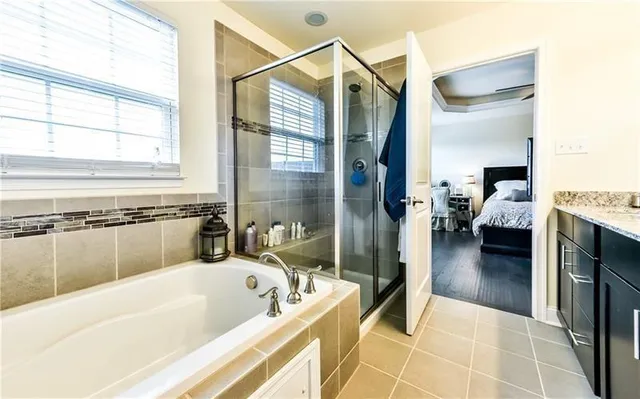 a en suite bathroom with a tub double vanity and window