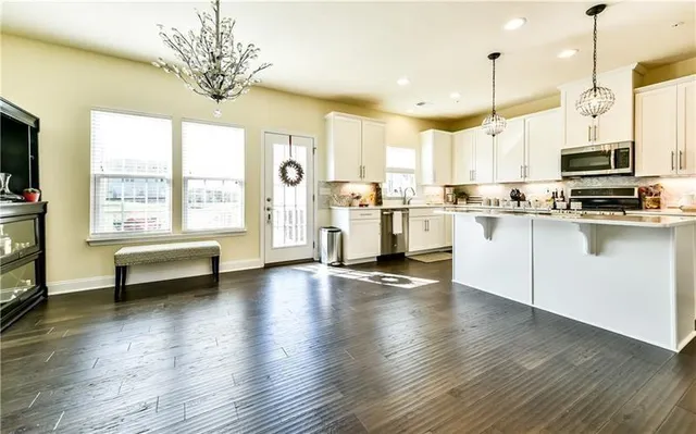 a view of a kitchen with kitchen island wooden floor and stainless steel appliances