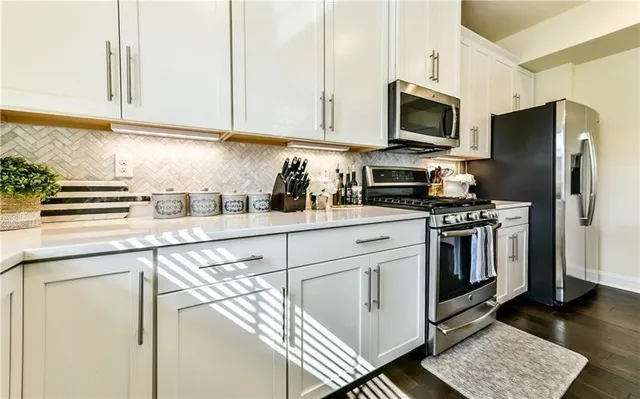 a kitchen with stainless steel appliances a sink a stove a microwave and cabinets