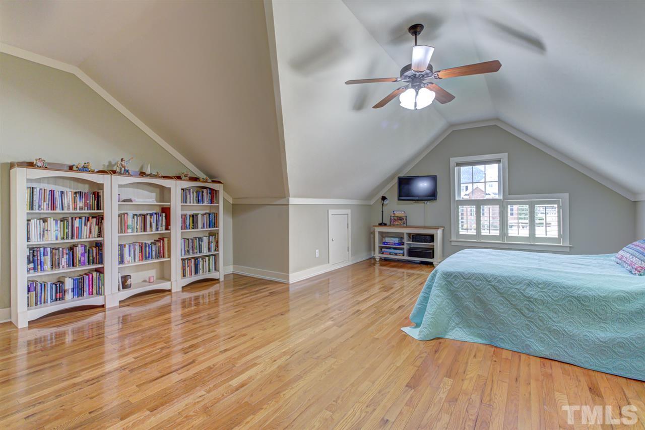 4609 Swordfish Drive Raleigh, NC 27603 - Photo 22 of 30 a spacious bedroom with a bed and a bookshelf with wooden floor