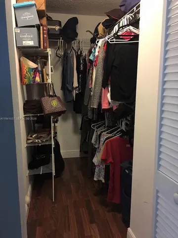 a view of walk in closet with clothes and shoes